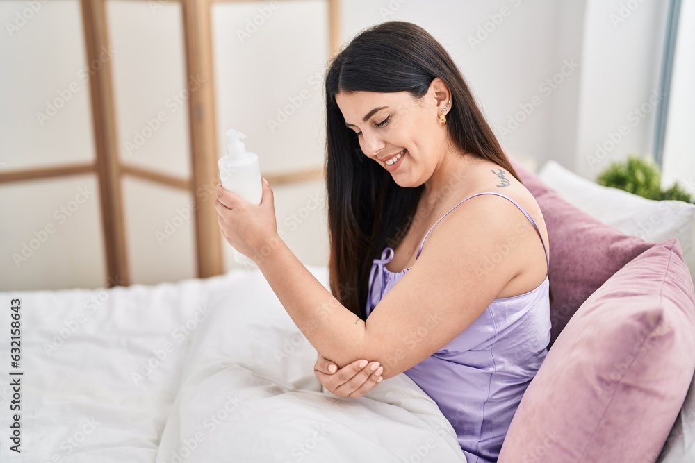 Young hispanic woman applying skin treatment sitting on bed at bedroom Young hispanic woman applying skin treatment sitting on bed at bedroom