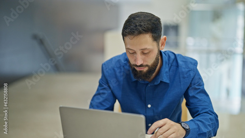 Young hispanic man business worker using laptop working at the office