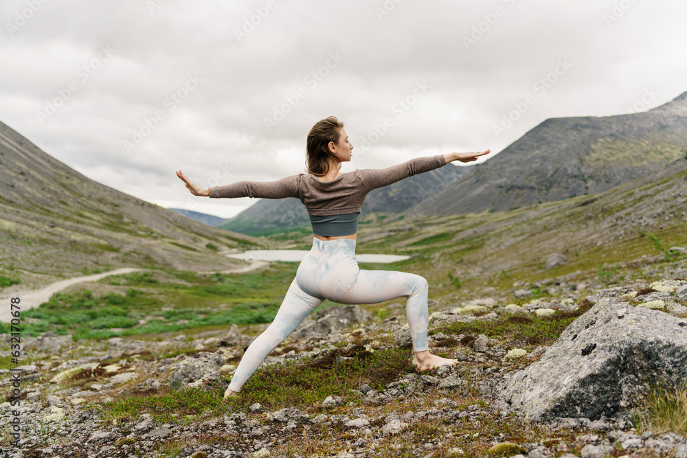 A slender woman is a trainer performing the exercise in the mountains in the nature of the north. Training in comfortable modern sportswear. Beautiful figure and flexible body. A slender woman is a trainer performing the exercise in the mountains in the nature of the north. Training in comfortable modern sportswear. Beautiful figure and flexible body.