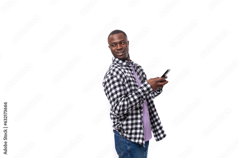 handsome young african man with short haircut in plaid shirt holding smartphone in hand handsome young african man with short haircut in plaid shirt holding smartphone in hand