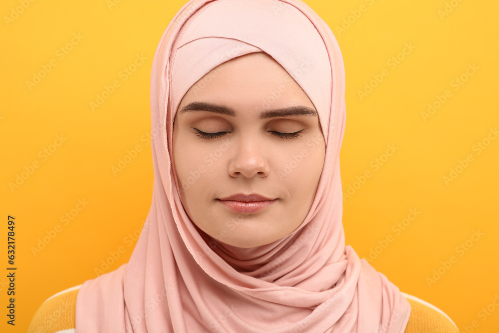 Portrait of Muslim woman in hijab on orange background Portrait of Muslim woman in hijab on orange background