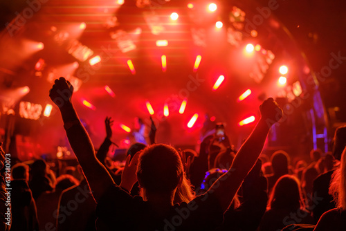 Fans with raised arms against glowing stage