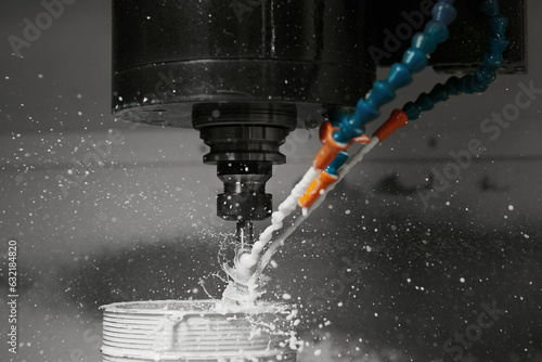 CNC milling machine cutting aluminium automotive part with a coolant liquid. Hi-Technology manufacturing process.  photo