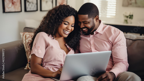 Happy black African-American couple on couch, applying for banking loan or mortgage, smiling and laughing. Ideal for home and personal loans.