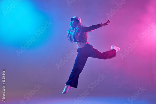 a girl in dark clothes dances on a neon background in smoke, modern dance © st.kolesnikov