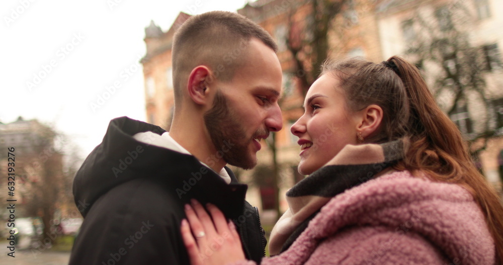 Close-up of the faces of a young couple in love kissing and hugging on the street on a gloomy autumn day. Close-up of the faces of a young couple in love kissing and hugging on the street on a gloomy autumn day.