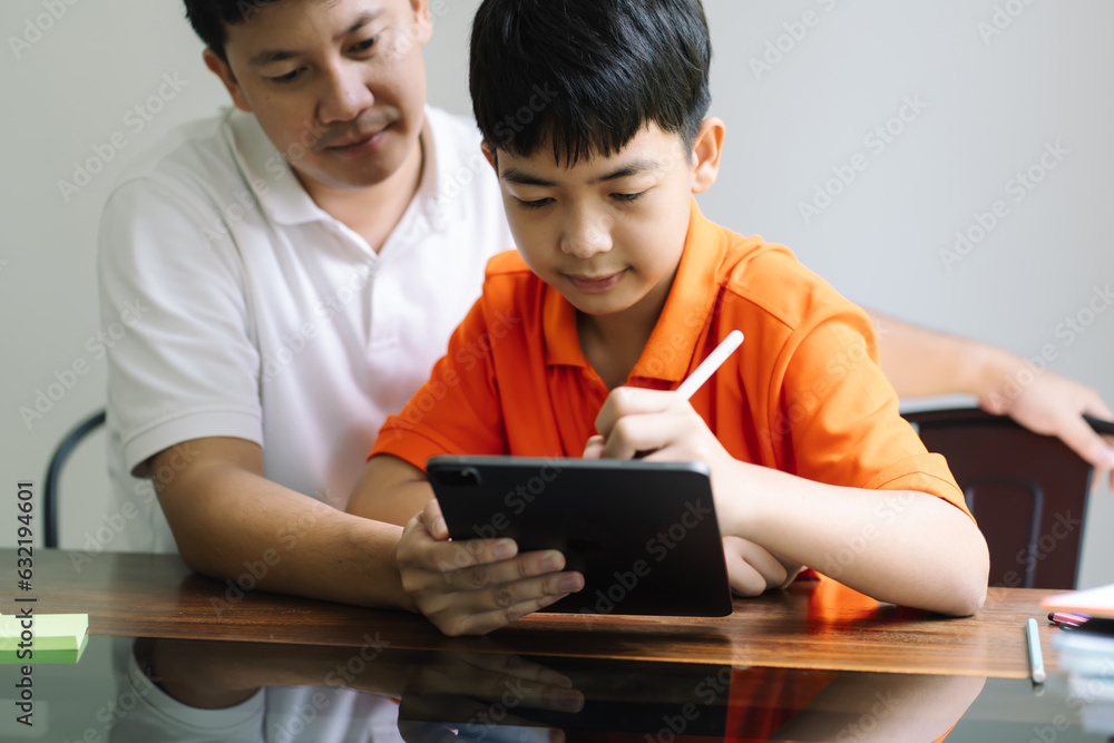 Asian father and son using tablet teaching son to draw.playing with digital tablet at desk fatherhood Asian father and son using tablet teaching son to draw.playing with digital tablet at desk fatherhood