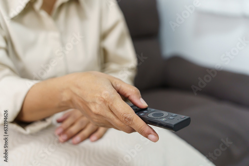 Elderly woman Watching smart TV and using remote controller Hand holding television audio remote control Middle age Asian woman movie Television series spending time at home