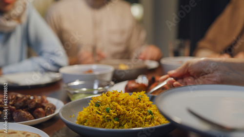 Close-up dish of halal food biryani rice on plate. Asia muslim sweet daughter serve food to mother Ramadan dinner together at home. Family celebration end of Eid al-Fitr togetherness at home.