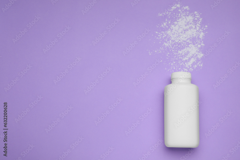Bottle and scattered dusting powder on violet background, top view with space for text. Baby cosmetic product Bottle and scattered dusting powder on violet background, top view with space for text. Baby cosmetic product