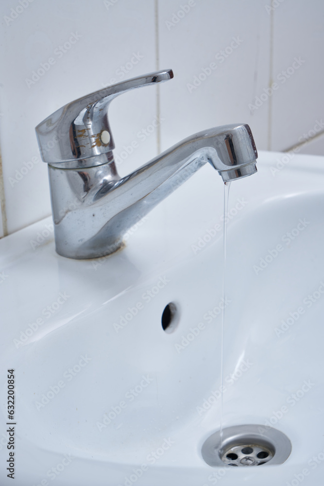 metallic faucet with running water in a white bathroom metallic faucet with running water in a white bathroom