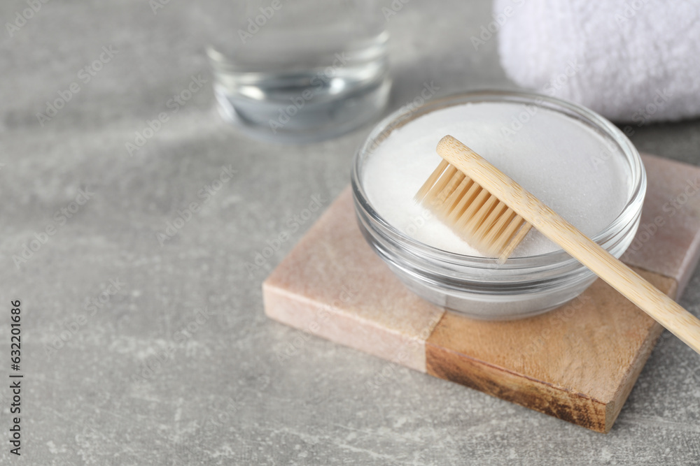 Bamboo toothbrush and glass bowl of baking soda on light grey table, space for text Bamboo toothbrush and glass bowl of baking soda on light grey table, space for text