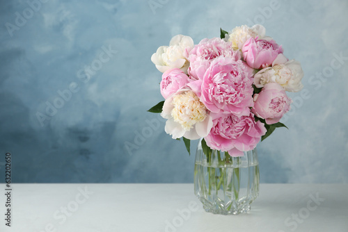 Fototapeta Naklejka Na Ścianę i Meble -  Beautiful peonies in glass vase on white table. Space for text
