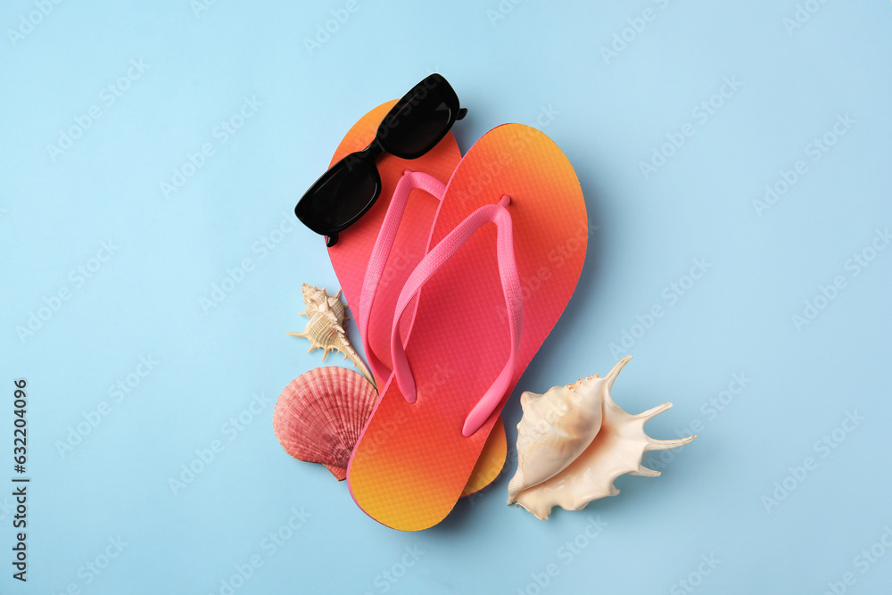 Sunglasses, flip flops and shells on light blue background, flat lay. Beach accessories - obrazy, fototapety, plakaty 
