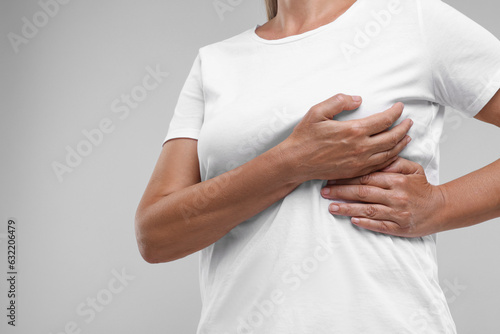Woman doing breast self-examination on light grey background, closeup. Space for text