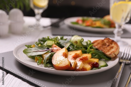 Delicious salad with peach slices served on table, closeup