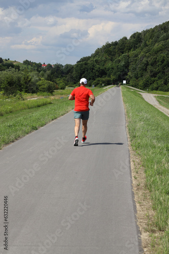 A runner in a red T-shirt, actively spends time in our air, in beautiful natural circumstances