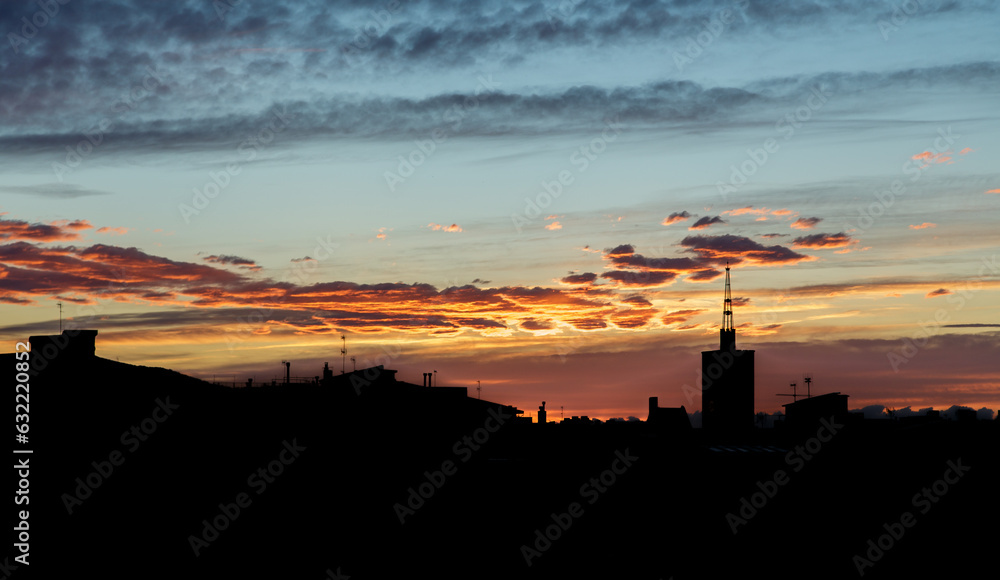 Horizontal shot of clouds floating across the sky with the setting sun on a spring evening over urban space. Concept of summer cityscapes. Copyspace