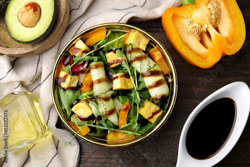 Delicious salad with tofu, vegetables and balsamic vinegar served on wooden table, flat lay