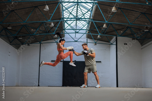 Female kickboxer does a knee strike mid air during her practice