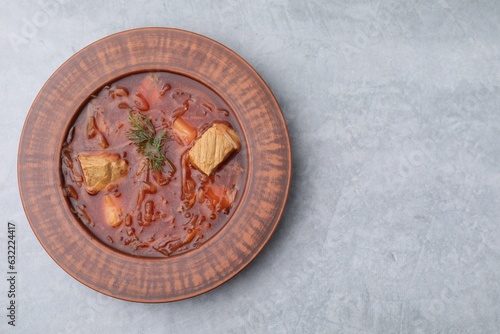 Bowl of delicious borscht on light grey table, top view. Space for text
