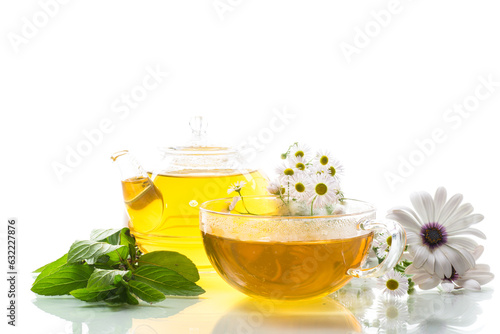 Chamomile flower tea in glass cup and teapot, on white background.
