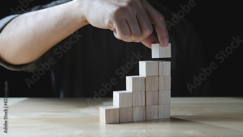 Business development to success. Businessman hand stacking wood block as step stair, business growth success on dark background. Concept of Business growth, Financial planning, Investment, Strategy