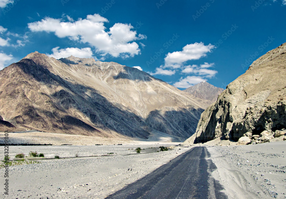 Mountains and flowing Shyok river with white clouds in blue sky background on way to Diskit in Nubra valley, Leh Mountains and flowing Shyok river with white clouds in blue sky background on way to Diskit in Nubra valley, Leh