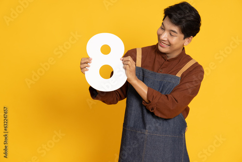 Restaurant owner sme young Asian man holding number 8 or eight isolated on yellow background photo