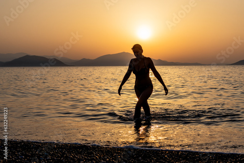 Tableau sur toile Silhouette of a woman stepping out of the sea or ocean at sunset.