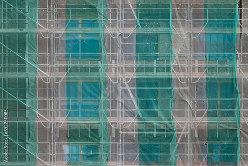 Building under construction covered in scaffolding with protective textile sheets