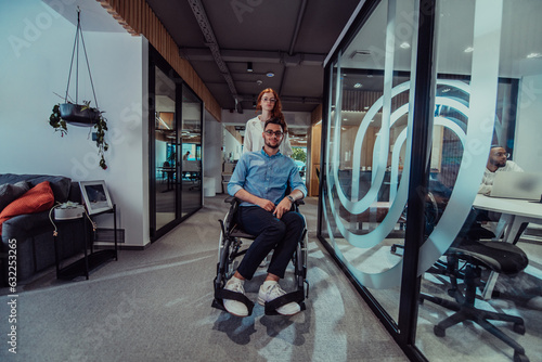 Young business colleagues, collaborative business colleagues, including a person in a wheelchair, walk past a modern glass office corridor, illustrating diversity, teamwork and empowerment in the