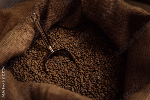 Photo From above of metal scoop in burlap bag filled with aromatic roasted coffee grai