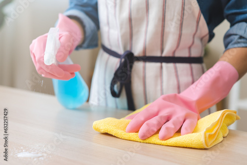 Cleanliness asian young woman working chore cleaning on table at home, hand wearing glove using rag rub remove dust with spray bottle. Household hygiene clean up, cleaner, equipment tool for cleaning