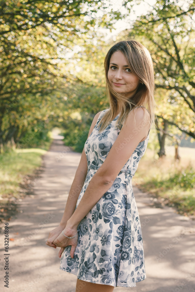 Beautiful smiling brunette woman in dress outdoors at the park alley. Beautiful smiling brunette woman in dress outdoors at the park alley.