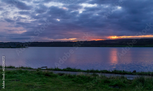 Sunset over Lochindorb and Lochindorb castle with reflection on the water of the loch photo