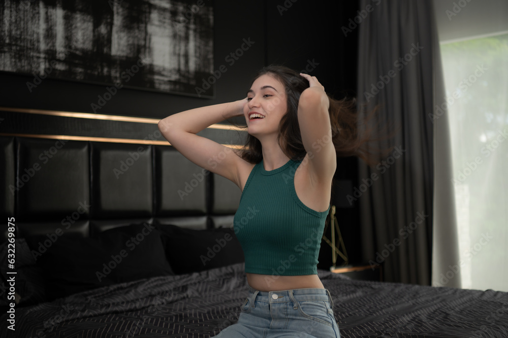 Young woman sitting on the bed in the room at night time. Young woman sitting on the bed in the room at night time.
