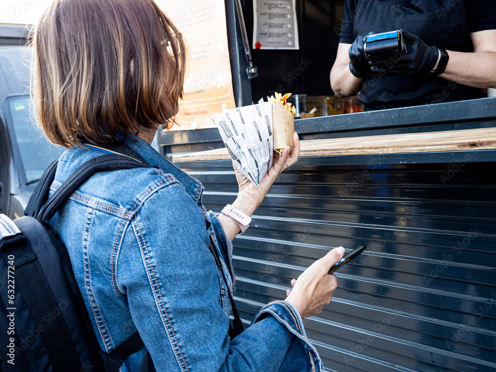 Woman paying with her smartphone for a hamburger during the food truck festival, Alicante, Valencian Community, Spain.