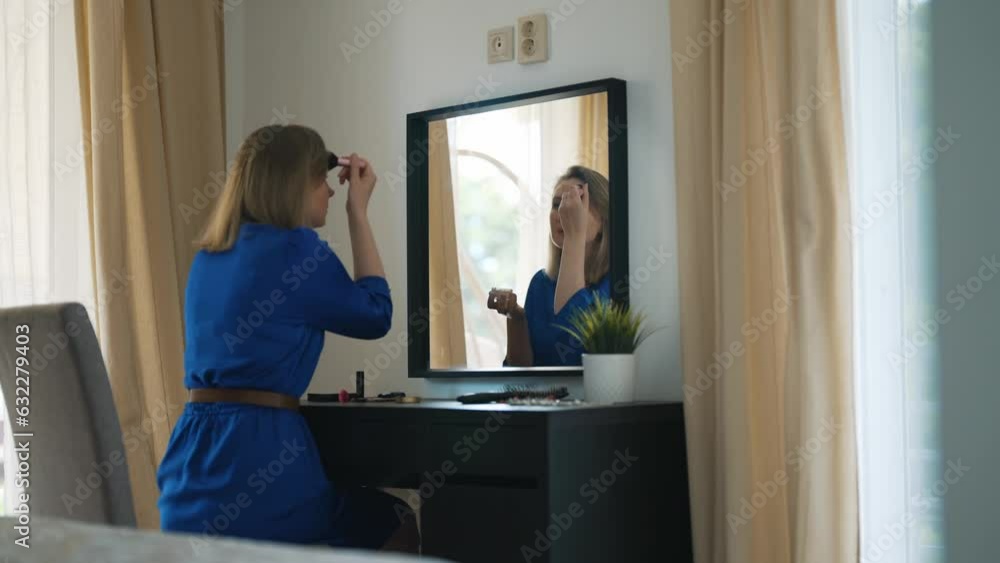 Woman doing makeup in front of mirror. Applying powder on face. Woman doing makeup in front of mirror. Applying powder on face.