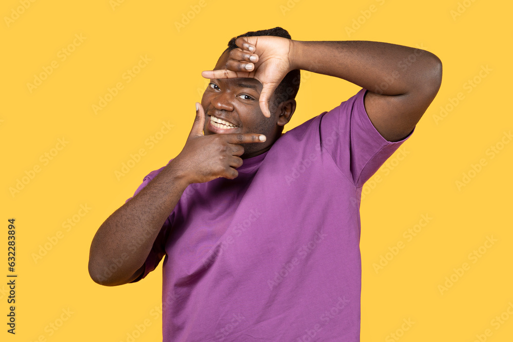 Happy black man making picture frame with fingers, yellow background Happy black man making picture frame with fingers, yellow background