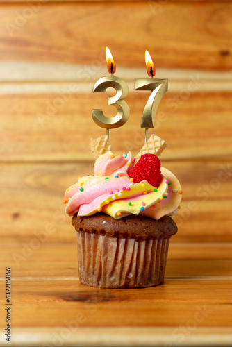 Golden birthday candle on wooden background - Birthday cupcake with numbered candle