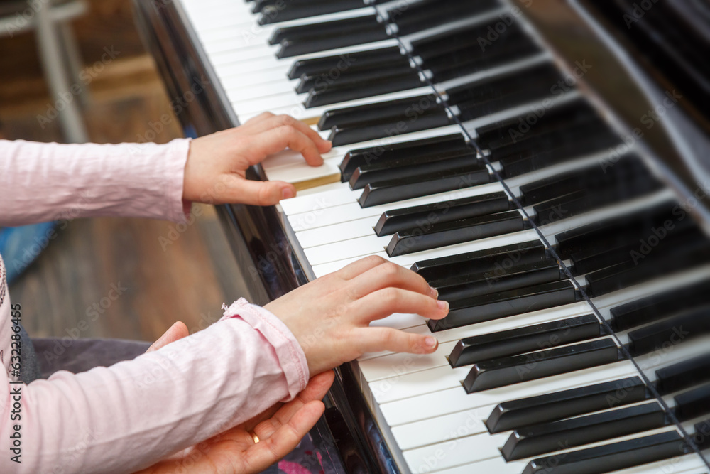 A child learns to play the piano with the help of a teacher.