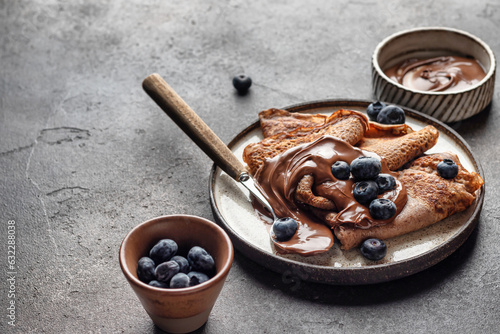 Stampa su tela Chocolate crepes with blueberry and chocolate paste on brown textured background