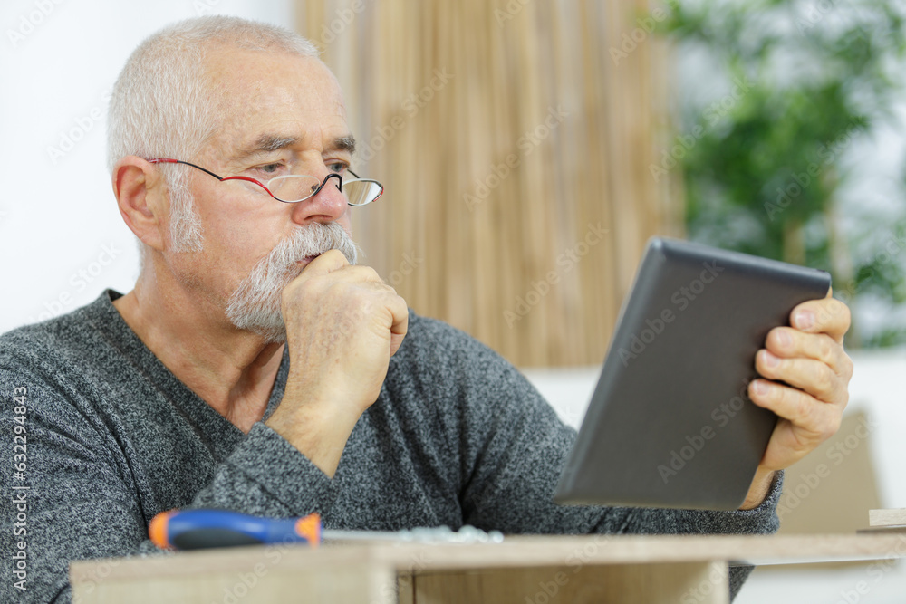 waist up portrait of senior carpenter using tablet