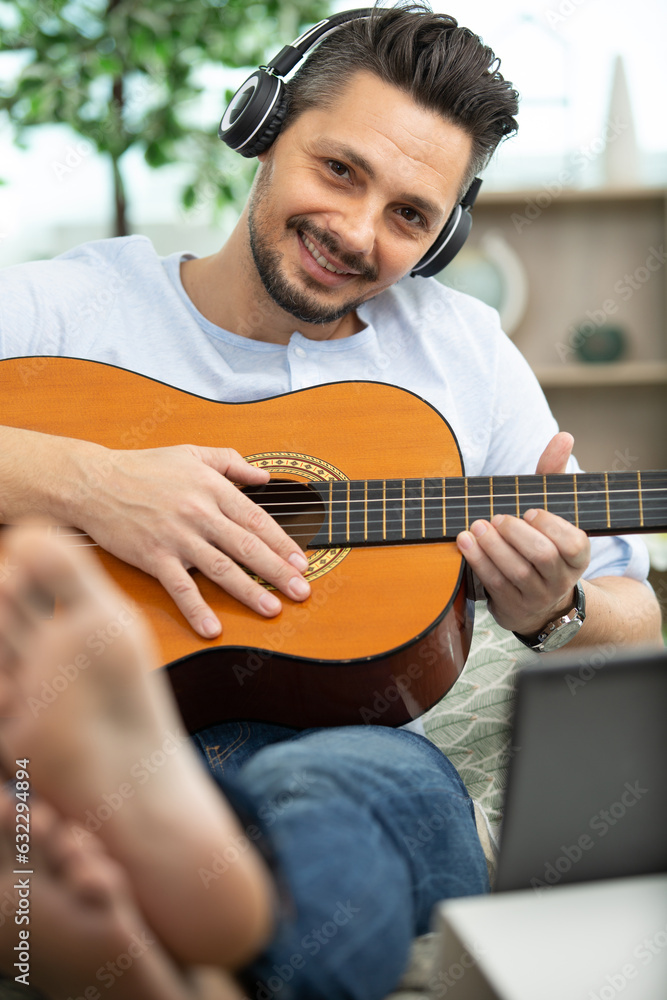 guy in headphones is playing guitar using a laptop