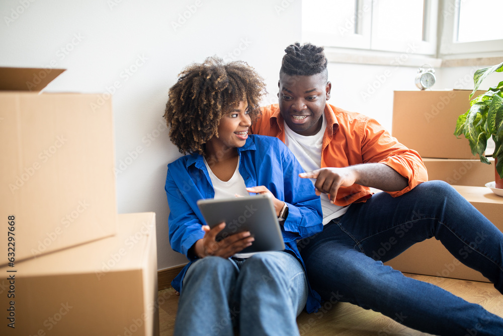 Smiling Black Spouses Using Digital Tablet While Relocating To New Apartment Smiling Black Spouses Using Digital Tablet While Relocating To New Apartment