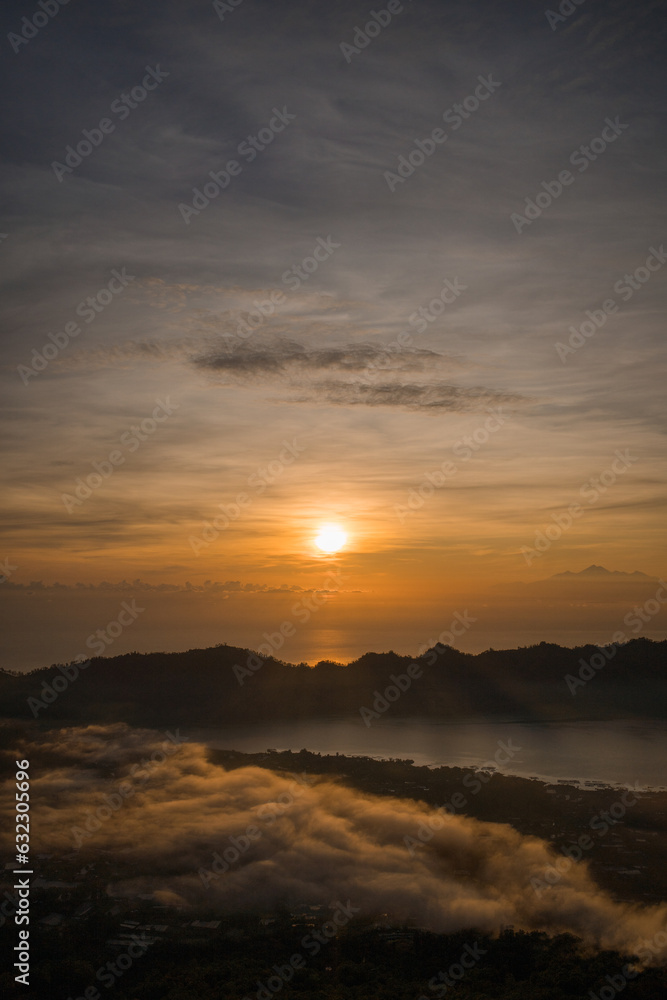 Amazing sunrise lake view at mount Batur. Dawns landscape photo at foggy Batur mount with orange sky