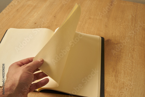 A white male hand turning the blank pages of a diary, notebook.