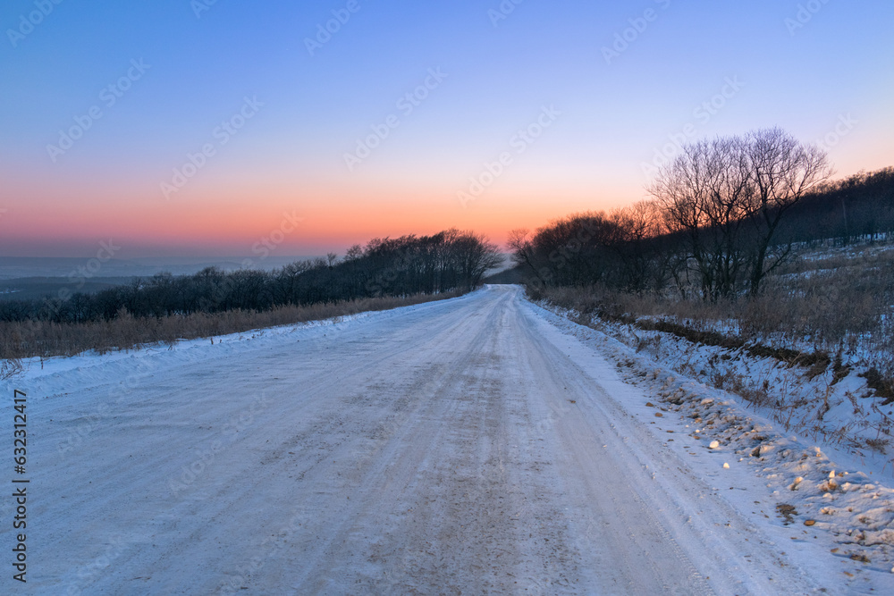 Winter landscape. Twilight over the hills that are covered with snow. Road on the hill during sunset. Winter landscape. Twilight over the hills that are covered with snow. Road on the hill during sunset.