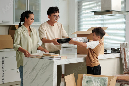 Cheerful parents asking son to put wrapped pictures in cardboard boxes